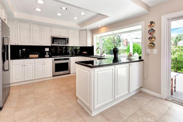 28021 Paseo Reposo, San Juan Capistrano, CA 92675 - kitchen with appliances with stainless steel finishes, dark countertops, a peninsula, a raised ceiling, and plenty of natural light