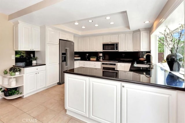28021 Paseo Reposo, San Juan Capistrano, CA 92675 - kitchen featuring appliances with stainless steel finishes, a raised ceiling, a peninsula, dark countertops, and recessed lighting