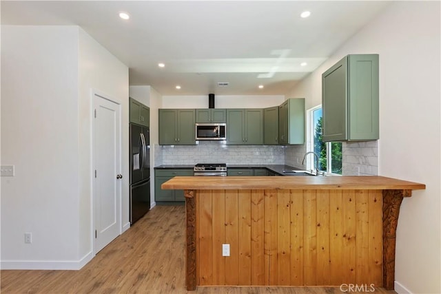 26182 Sky Ridge Dr, Twin Peaks, CA 92391 - kitchen featuring green cabinets, appliances with stainless steel finishes, tasteful backsplash, a peninsula, and light wood finished floors