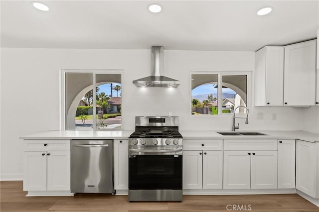 2852 E San Angelo Rd, Palm Springs, CA 92262 - kitchen with appliances with stainless steel finishes, wall chimney exhaust hood, white cabinetry, light countertops, and recessed lighting