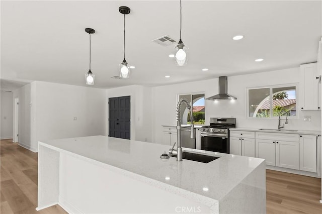 2852 E San Angelo Rd, Palm Springs, CA 92262 - kitchen featuring stainless steel gas stove, wall chimney range hood, light wood-style flooring, white cabinets, and light stone counters