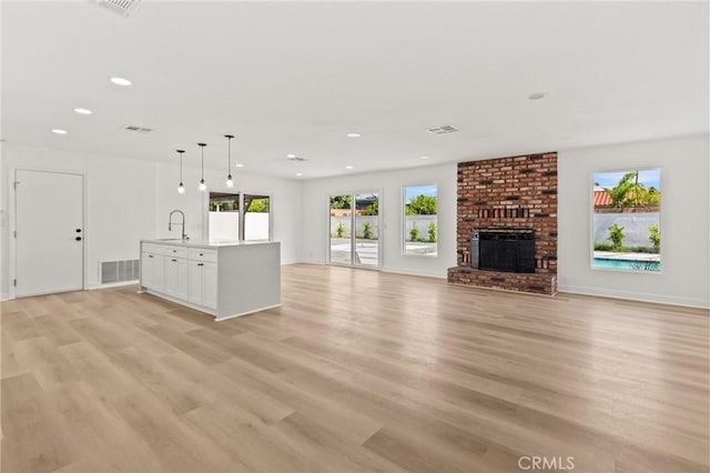 2852 E San Angelo Rd, Palm Springs, CA 92262 - unfurnished living room with light wood-type flooring, recessed lighting, and a brick fireplace