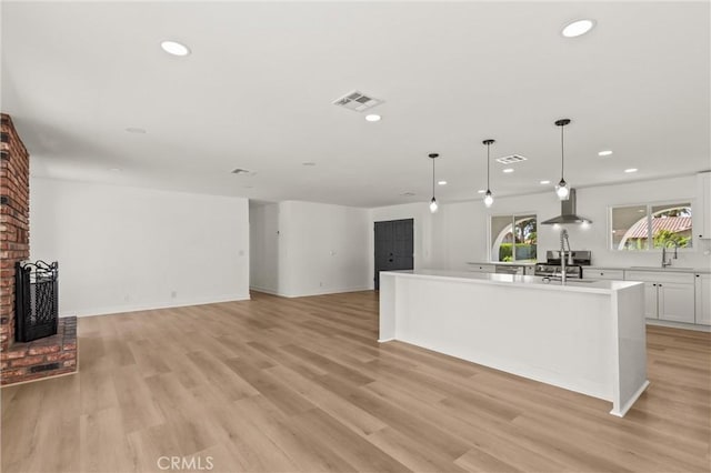 2852 E San Angelo Rd, Palm Springs, CA 92262 - kitchen with wall chimney exhaust hood, white cabinetry, a center island with sink, recessed lighting, and light countertops