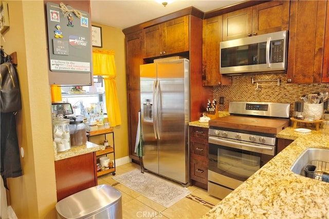4140 Workman Mill Rd Unit 234, Whittier, CA 90601 - kitchen featuring stainless steel appliances, light tile patterned flooring, backsplash, light stone counters, and brown cabinets