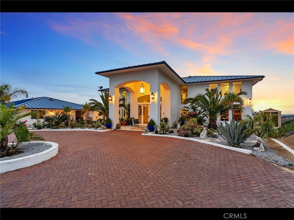 31460 Aquaduct Rd, Bonsall, CA 92003 - mediterranean / spanish house featuring stucco siding, curved driveway, a standing seam roof, and a metal roof
