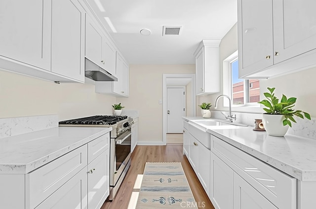 531 7th, Bakersfield, CA 93304 - kitchen with high end range, under cabinet range hood, light wood-style floors, and white cabinets