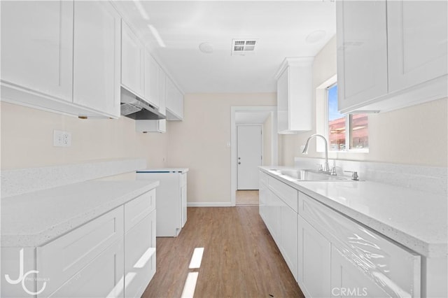 531 7th, Bakersfield, CA 93304 - kitchen with white cabinetry, under cabinet range hood, light wood-style floors, and light stone countertops