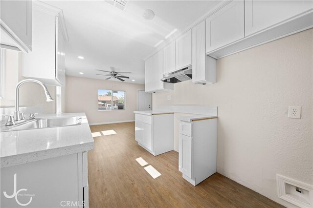 531 7th, Bakersfield, CA 93304 - kitchen featuring under cabinet range hood, light wood-style flooring, a ceiling fan, white cabinetry, and light stone counters
