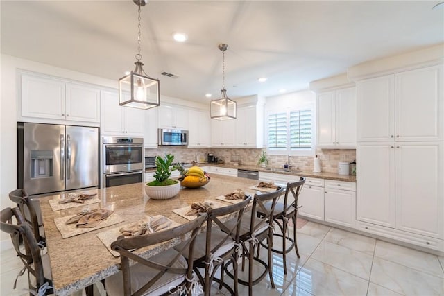 13211 Baxter Springs Dr, Rancho Cucamonga, CA 91739 - kitchen with appliances with stainless steel finishes, a breakfast bar area, white cabinetry, and recessed lighting