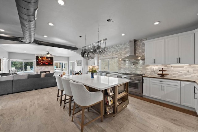 3676 Valley Rd, Bonita, CA 91902 - kitchen with wall chimney range hood, stainless steel appliances, a kitchen island, light wood-type flooring, and white cabinets