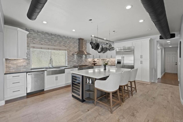 3676 Valley Rd, Bonita, CA 91902 - kitchen with wall chimney exhaust hood, stainless steel appliances, wine cooler, white cabinetry, and decorative backsplash
