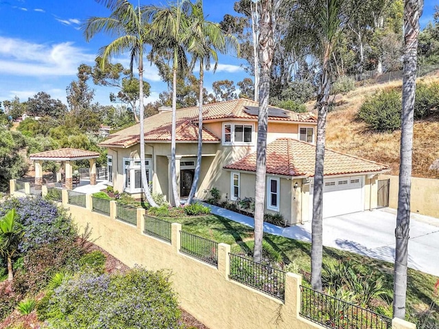 3676 Valley Rd, Bonita, CA 91902 - rear view of house with stucco siding, roof mounted solar panels, a tile roof, concrete driveway, and an attached garage