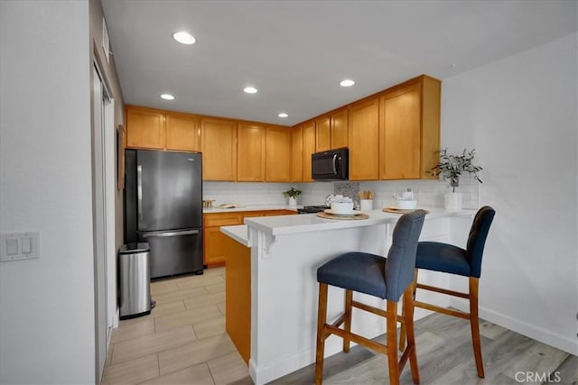 11 Exeter, Irvine, CA 92612 - kitchen with freestanding refrigerator, black microwave, a peninsula, decorative backsplash, and recessed lighting