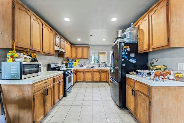 730 W 52nd Pl, Los Angeles, CA 90037 - kitchen featuring stainless steel appliances, under cabinet range hood, recessed lighting, light tile patterned floors, and tile counters