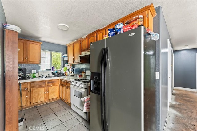 730 W 52nd Pl, Los Angeles, CA 90037 - kitchen with fridge with ice dispenser, white gas range, under cabinet range hood, a textured ceiling, and tile countertops