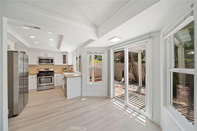 35 Havenwood Unit 83, Irvine, CA 92614 - kitchen featuring stainless steel appliances, white cabinetry, light wood-type flooring, a tray ceiling, and lofted ceiling