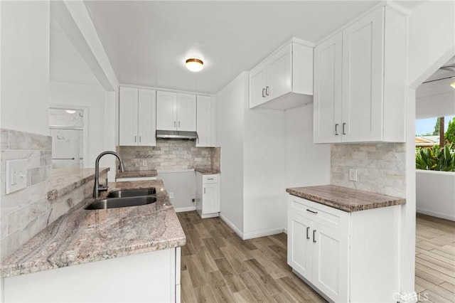 9912 Marshall St, El Monte, CA 91731 - kitchen featuring light stone counters, under cabinet range hood, backsplash, light wood-style floors, and white cabinets