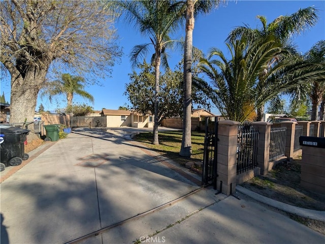 10051 Orchard St, Bloomington, CA 92316 - obstructed view of property featuring a gate, concrete driveway, and stucco siding