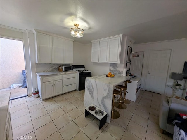 10051 Orchard St, Bloomington, CA 92316 - kitchen featuring gas range oven, stainless steel microwave, light countertops, white cabinetry, and ornamental molding