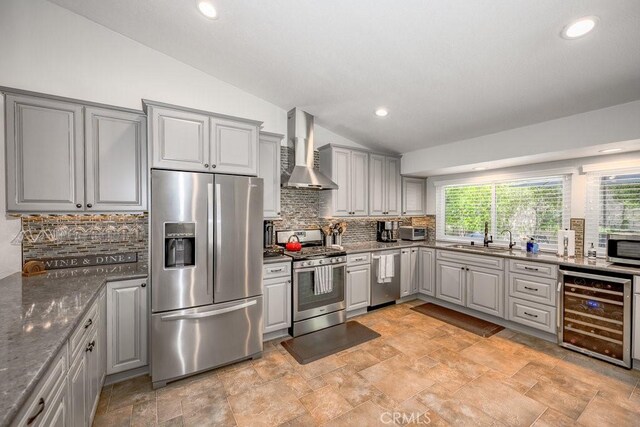 27817 Wakefield Rd, Castaic, CA 91384 - kitchen with stainless steel appliances, wall chimney exhaust hood, beverage cooler, gray cabinetry, and vaulted ceiling
