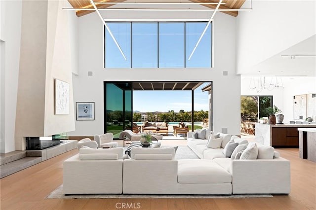 25151 Jim Bridger Rd, Hidden Hills, CA 91302 - living area featuring wood finished floors, a chandelier, a towering ceiling, and a fireplace with raised hearth