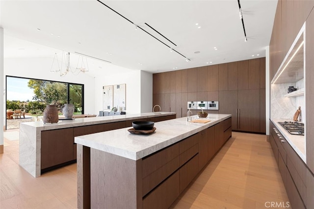 25151 Jim Bridger Rd, Hidden Hills, CA 91302 - kitchen with modern cabinets, a spacious island, stainless steel gas stovetop, light wood-style floors, and recessed lighting