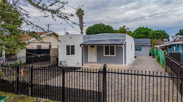 323 E 93rd St, Los Angeles, CA 90003 - bungalow-style home with stucco siding, a fenced front yard, and a porch