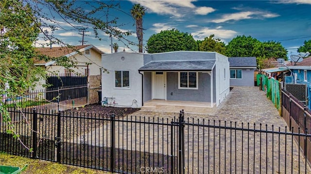 323 E 93rd St, Los Angeles, CA 90003 - view of front of house featuring stucco siding, covered porch, a shingled roof, and a fenced front yard