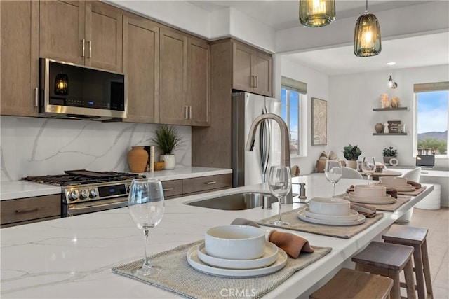 7348 Foster Bridge Blvd, Downey, CA 90240 - kitchen with stainless steel appliances, light stone countertops, a breakfast bar, hanging light fixtures, and tasteful backsplash