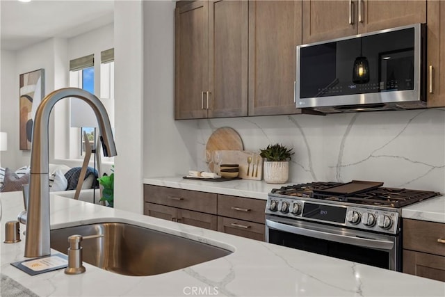 7348 Foster Bridge Blvd, Downey, CA 90240 - kitchen with appliances with stainless steel finishes, tasteful backsplash, light stone counters, and dark brown cabinets