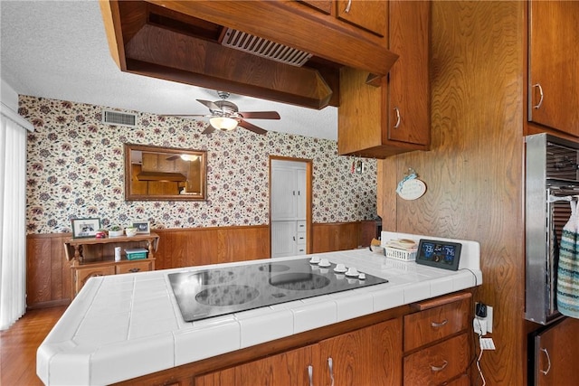 1419 S 4th Ave, Arcadia, CA 91006 - kitchen featuring tile countertops, a wainscoted wall, brown cabinetry, wallpapered walls, and a ceiling fan