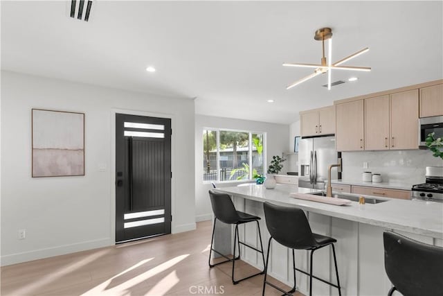 12934 Fenton Ave, Sylmar, CA 91342 - kitchen featuring stainless steel appliances, light brown cabinets, a kitchen breakfast bar, light stone countertops, and recessed lighting