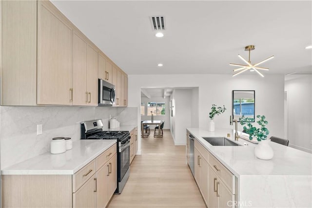 12934 Fenton Ave, Sylmar, CA 91342 - kitchen with appliances with stainless steel finishes, light brown cabinetry, an island with sink, tasteful backsplash, and light wood-style floors