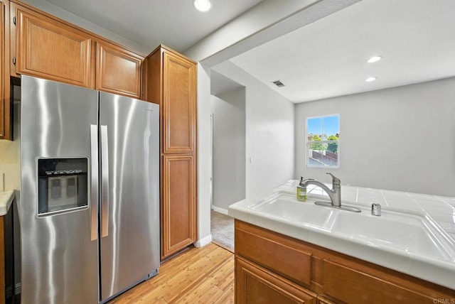 2755 Castlehill Rd Unit 1, Chula Vista, CA 91915 - kitchen with stainless steel fridge with ice dispenser, light wood finished floors, recessed lighting, brown cabinetry, and tile countertops
