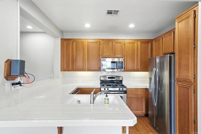 2755 Castlehill Rd Unit 1, Chula Vista, CA 91915 - kitchen featuring stainless steel appliances, a peninsula, tile countertops, recessed lighting, and brown cabinetry