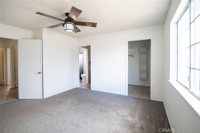 9018 Buckthorn Ave, Hesperia, CA 92345 - unfurnished bedroom with carpet flooring, multiple windows, tile patterned floors, a textured ceiling, and ensuite bathroom