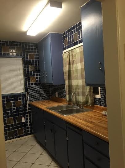 45040 Redwood Ave, Lancaster, CA 93534 - kitchen featuring tile walls, wood counters, light tile patterned floors, and tasteful backsplash