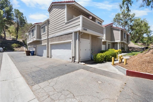 31319 The Old Rd Unit A, Castaic, CA 91384 - view of home's exterior featuring an attached garage, driveway, stucco siding, and a tiled roof
