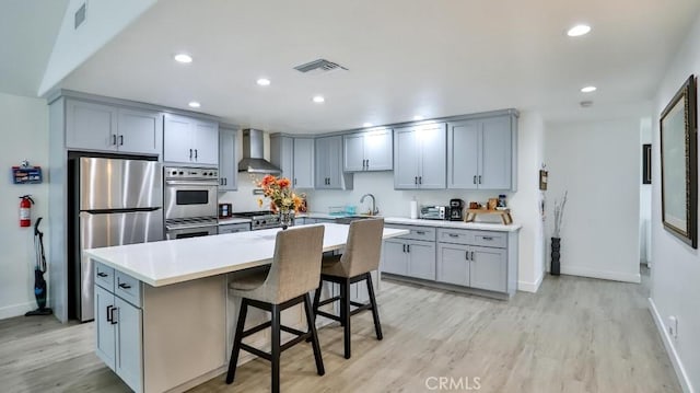 10361 Perdido St, Anaheim, CA 92804 - kitchen featuring stainless steel appliances, wall chimney exhaust hood, light wood-style flooring, gray cabinetry, and recessed lighting