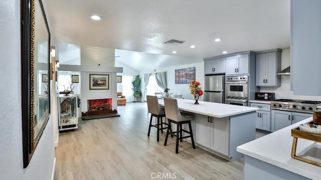 10361 Perdido St, Anaheim, CA 92804 - kitchen featuring stainless steel appliances, gray cabinetry, light wood-style floors, a breakfast bar area, and a center island
