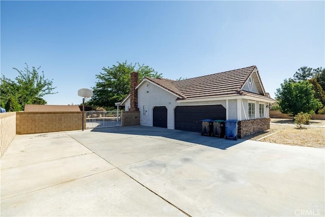 3807 Paula Ln, Lancaster, CA 93535 - view of property exterior featuring an attached garage, stucco siding, driveway, a chimney, and a gate