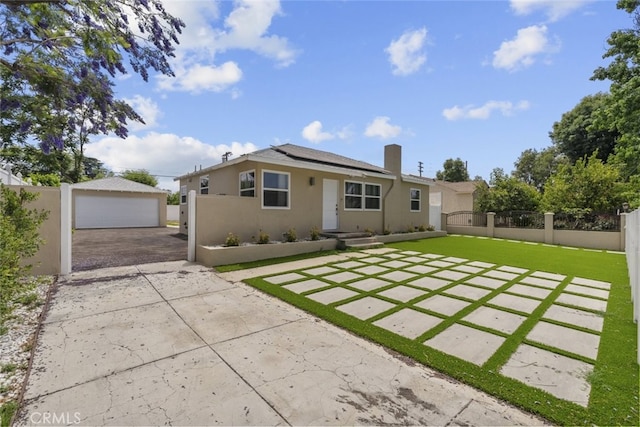 6820 Jellico Ave, Van Nuys, CA 91406 - view of front of home featuring roof mounted solar panels, a garage, stucco siding, a chimney, and an outdoor structure