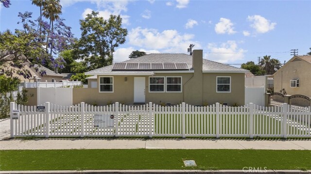 6820 Jellico Ave, Van Nuys, CA 91406 - bungalow-style home featuring solar panels, stucco siding, a fenced front yard, and roof with shingles