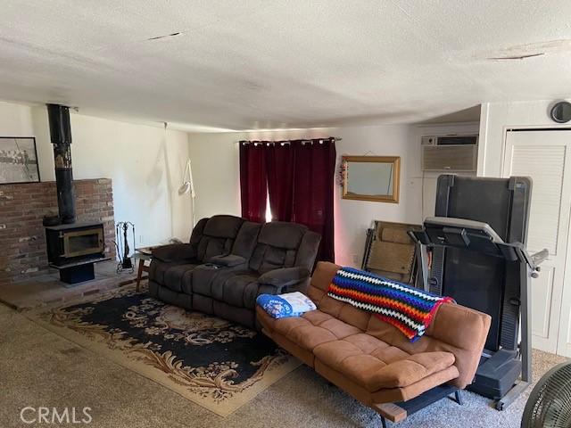 7 Westwood Way, Oroville, CA 95966 - living room featuring carpet flooring, a wood stove, a wall mounted AC, and a textured ceiling