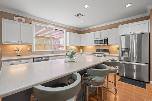 5191 Cobalt Way, Oceanside, CA 92057 - kitchen featuring stainless steel appliances, white cabinetry, crown molding, a kitchen breakfast bar, and light wood-style flooring