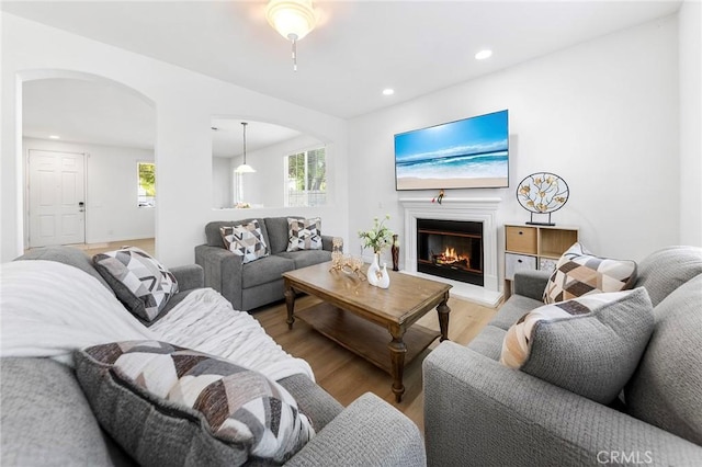 15216 Masline St, Baldwin Park, CA 91706 - living room featuring arched walkways, light wood-style floors, recessed lighting, and a glass covered fireplace