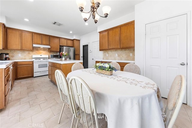 15216 Masline St, Baldwin Park, CA 91706 - kitchen featuring white gas range oven, freestanding refrigerator, under cabinet range hood, a chandelier, and a kitchen island