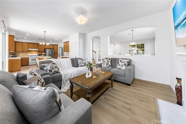 15216 Masline St, Baldwin Park, CA 91706 - living room with arched walkways, light wood finished floors, recessed lighting, and a chandelier