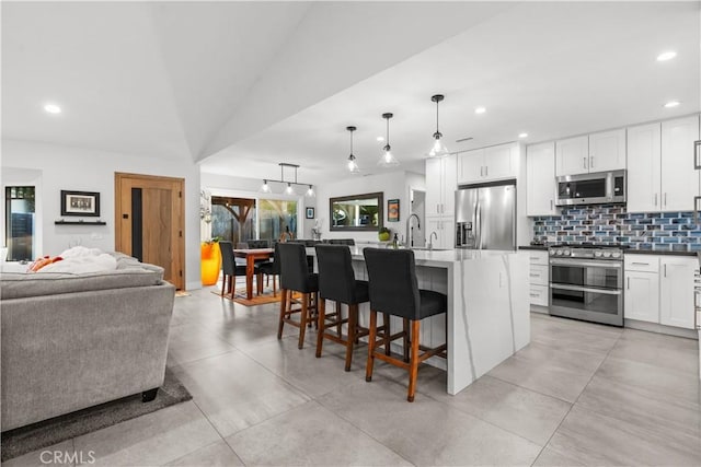 25891 Pinewood Ln, Laguna Hills, CA 92653 - kitchen featuring appliances with stainless steel finishes, open floor plan, backsplash, recessed lighting, and a kitchen breakfast bar