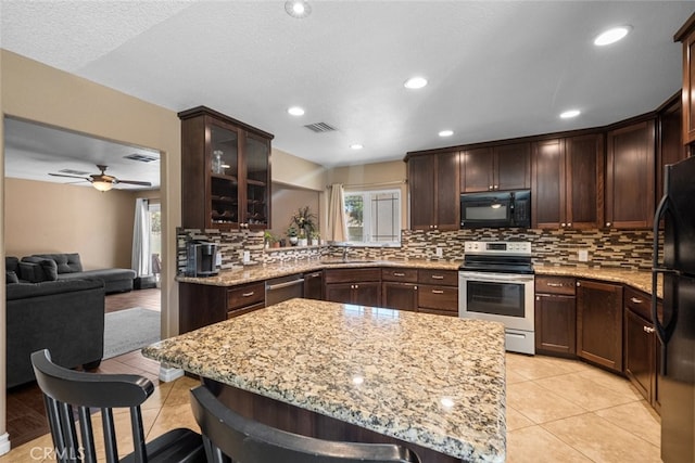 44112 Precise St, Lancaster, CA 93536 - kitchen featuring black appliances, backsplash, dark brown cabinets, light stone counters, and light tile patterned floors